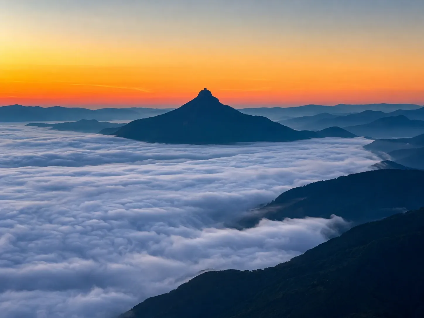 The conical summit of Adam's Peak (Sri Pada) rising above a sea of cloud at sunrise, Sri Lanka